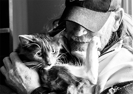 Older Man with beard, long hair and hat holding his cat